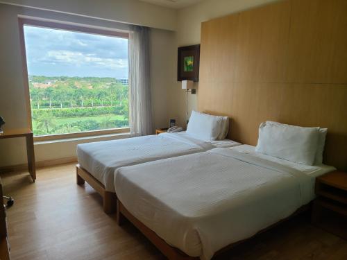 a bedroom with a large bed with a large window at Novotel Hyderabad Airport in Hyderabad