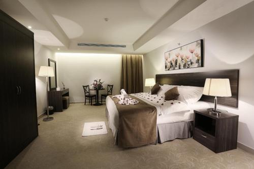 a bedroom with a large bed and a table at Hayat Watheer for serviced Apartment in Dammam