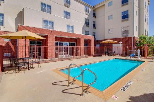 a swimming pool with a table and chairs and a building at MainStay Suites Texas Medical Center-Reliant Park in Houston