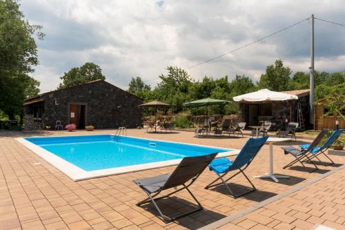 a swimming pool with chairs and an umbrella at Viola Nel Parco in SantʼAlfio