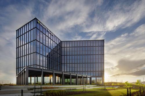 a large glass building with the sun in the sky at Hyatt Place Melbourne Caribbean Park in Scoresby