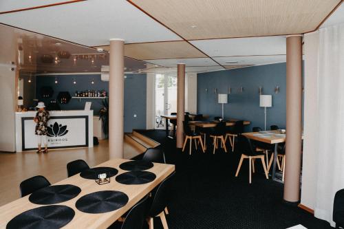 a dining room with tables and chairs and a bar at Hotel Vesiroos in Pärnu