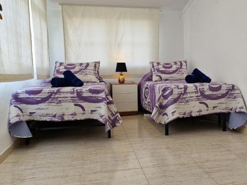 a bedroom with two beds with purple and white sheets at Riumar "La Pinya", 500m to beach, Privat-Pool, On-Site-Service, dog beach in Riumar