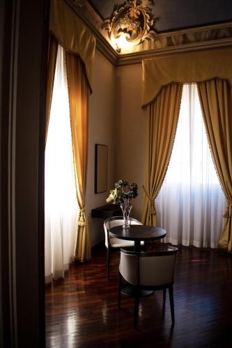a dining room with a table and two windows at Bosone Palace in Gubbio