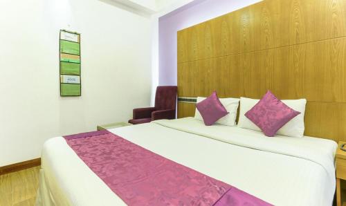 a hotel room with a bed with purple pillows at Medora Hotel in Kozhikode