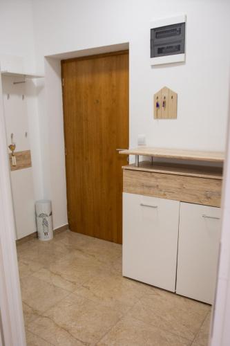 a kitchen with white cabinets and a wooden door at Apartman Maša in Šibenik