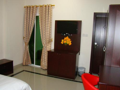 a hotel room with a television and a red chair at Savoy Grand Hotel Apartments in Muscat