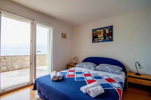 a bedroom with a blue bed and a large window at Beach House Splitska in Splitska