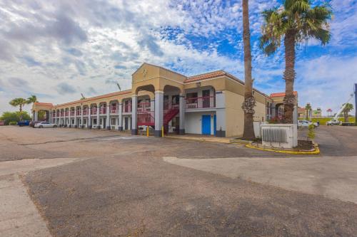 a large building with palm trees in a parking lot at Coastal Inn Corpus Christi in Corpus Christi