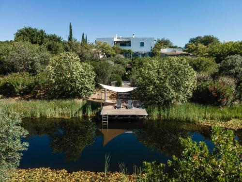 a dock in the middle of a lake with trees at Altanure Casa Terra - Ecological Boutique Stay in Tavira