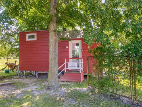 una casa roja con un árbol delante en Tiny House auf der Alpaka Farm en Rubkow