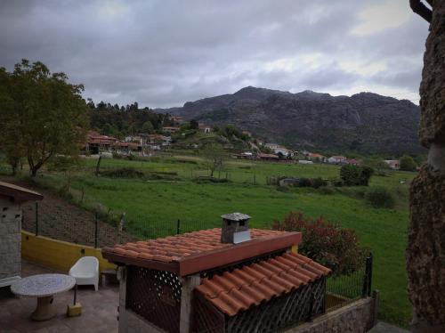 a house with a view of a green field and mountains at Casa de Fundevila in Campo do Gerês