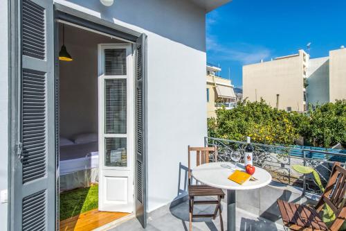 patio con mesa blanca y sillas y balcón en Greenhouse - Kalamata Mediterranean Villas, en Kalamata