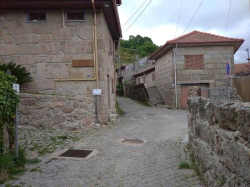 an alley with a stone wall and a building at Casa de Fundevila in Campo do Gerês