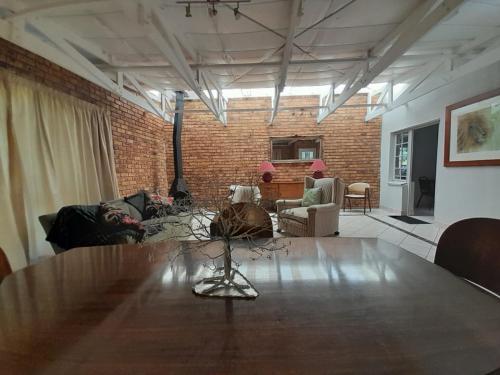 a living room with a table and a brick wall at UppaTree Cottage in Benoni