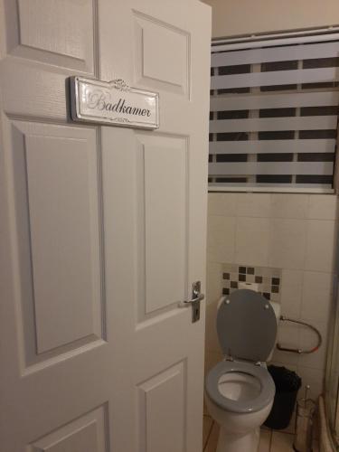 a bathroom door with a toilet and a sign on it at UppaTree Cottage in Benoni