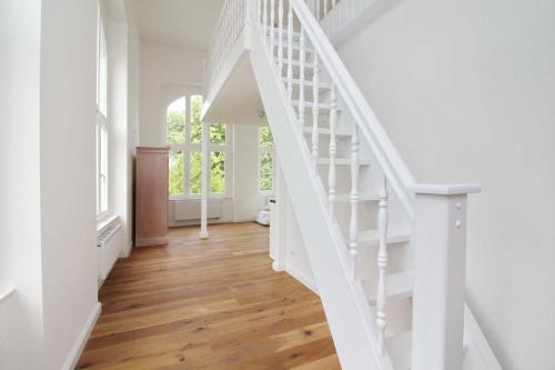 a white staircase in a home with wooden floors at Schloss Hohendorf in Groß Mohrdorf