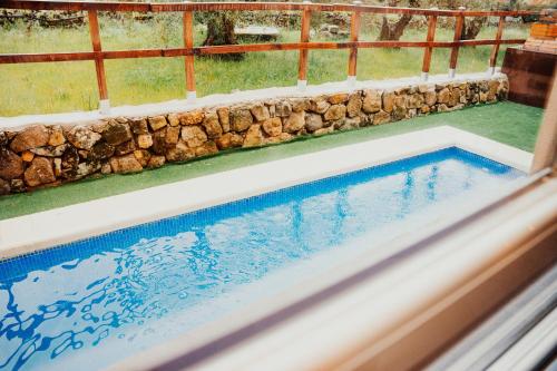 a swimming pool with a rock retaining wall and a swimming pool at El Refugio de Felix in Sotillo de la Adrada