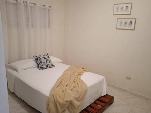 a white bedroom with a bed with a blanket on it at La Casa de Mamá in San Fernando de Monte Cristi