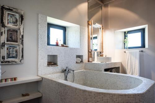 un bagno bianco con vasca e 2 finestre di Altanure - Casa Terra Ecological Boutique Hotel a Tavira