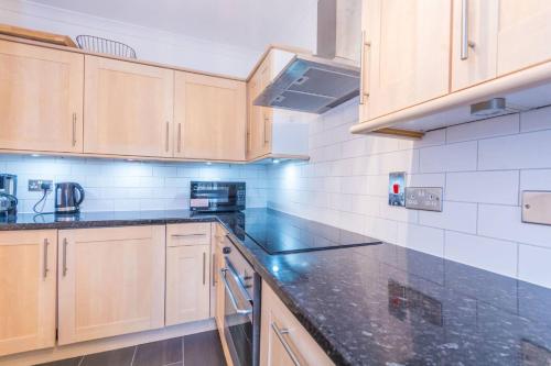 a kitchen with wooden cabinets and a black counter top at St Johns Wood 1 Bedroom Apartment in London