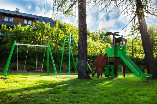 a playground with a green slide and two trees at DW Halicz in Solina