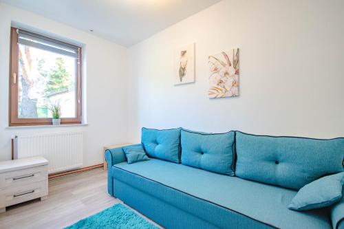 a blue couch in a living room with a window at Pod Brzozami - domek nad jeziorem Białym in Orchówek