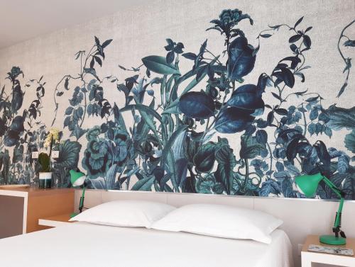 a bedroom with a wall mural of plants at Hotel Grecale in Porto Cesareo