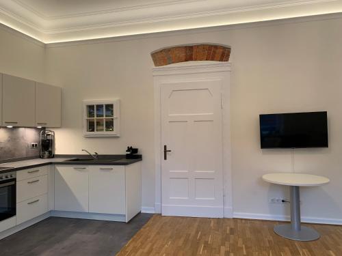a kitchen with a white door and a table at Remedium Appartements in Vlotho