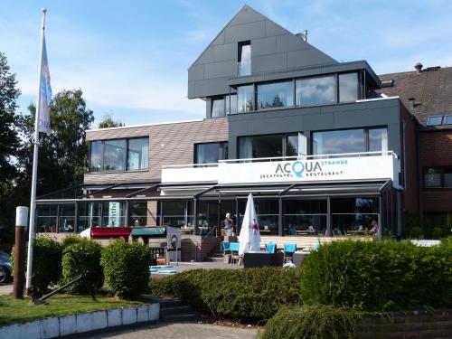 um edifício com uma bandeira à sua frente em ACQUA Strande Yachthotel & Restaurant em Strande