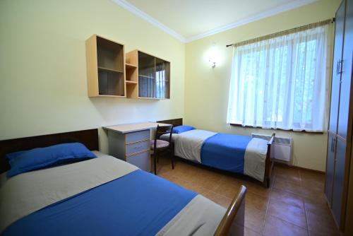 a hotel room with two beds and a desk at Sevan Tarsus Guesthouse in Tsovazard