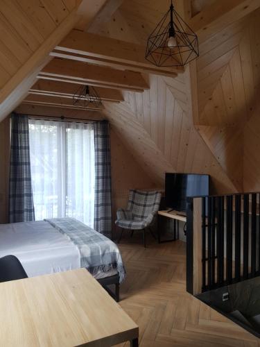 Un dormitorio con una cama y un escritorio y una ventana. en Apartamenty BENITA, en Zakopane