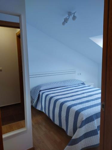 a bedroom with a bed with a blue and white striped blanket at VIVIENDA BOCA DO RIO- Carnota in Carnota