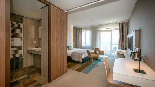 a hotel room with a bed and a bathroom at Strandhotel Golfzang in Egmond aan Zee
