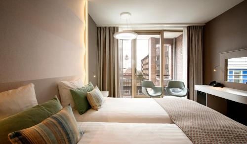 a hotel room with a large bed and a window at Strandhotel Golfzang in Egmond aan Zee
