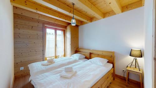 a bedroom with a large white bed in a wooden wall at Chalet des Alpes NATURE & MOUNTAIN by Alpvision Résidences in Prarion