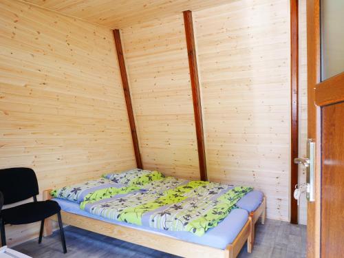 a bed in a room with a wooden wall at Camping Rožnov in Rožnov pod Radhoštěm