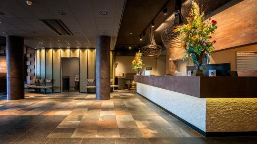 a lobby of a hotel with a reception desk and flowers at Strandhotel Golfzang in Egmond aan Zee