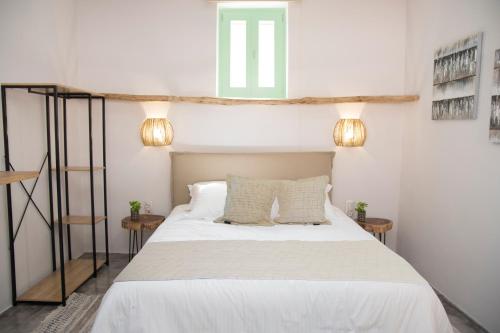 a bedroom with a bed with white sheets and a window at Siroa Easy in Ermoupoli