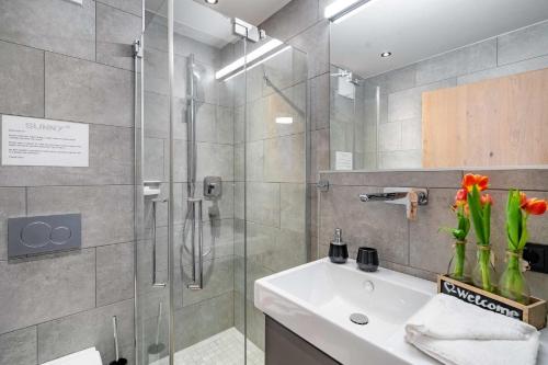 a bathroom with a shower and a sink and a glass shower stall at Sunny Ferienwohnungen Ski In - Ski Out - Self Check-in in Zell am See