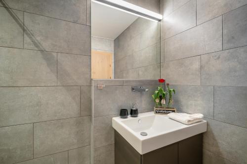 a bathroom with a white sink and a mirror at Sunny Ferienwohnungen Ski In - Ski Out - Self Check-in in Zell am See