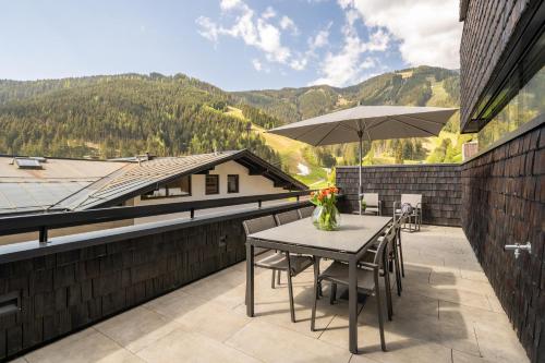 a patio with a table and an umbrella at Sunny Ferienwohnungen Ski In - Ski Out - Self Check-in in Zell am See