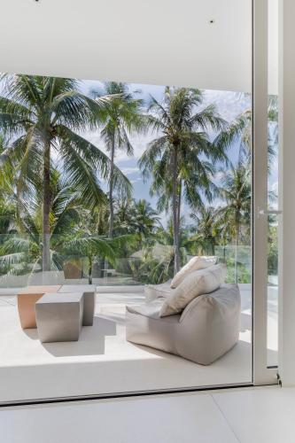 a living room with a white couch and palm trees at Anaia in Thongsala