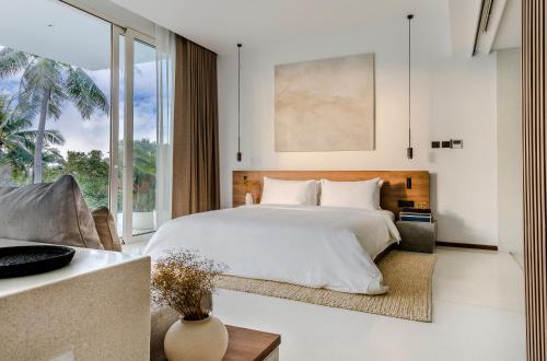 a bedroom with a large bed and a large window at Anaia in Thongsala