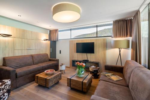 a living room with a couch and a tv at Sunny Ferienwohnungen Ski In - Ski Out - Self Check-in in Zell am See