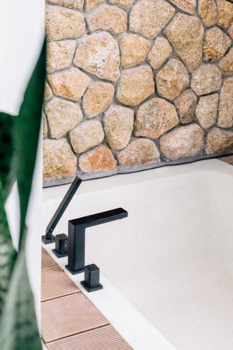 a black sink with a stone wall behind it at Anaia in Thongsala