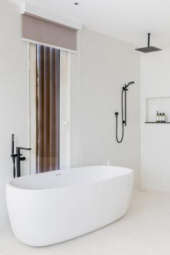 a white bathroom with a large white tub at Anaia in Thongsala