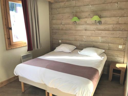 a bed in a bedroom with a wooden wall at Appartement Centre Skis aux Pieds, Parking & Animaux Acceptés - FR-1-513-77 in La Tania