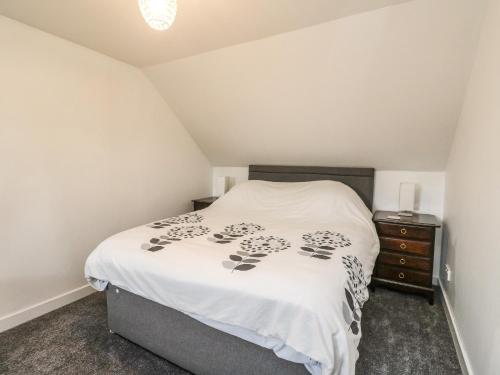 a bedroom with a white bed and a dresser at 6 Lowlands in Arisaig