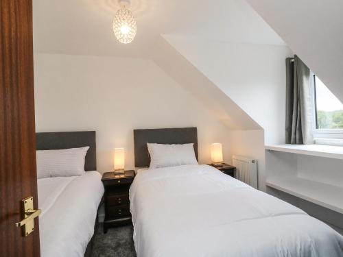 two beds in a bedroom with two lamps on tables at 6 Lowlands in Arisaig